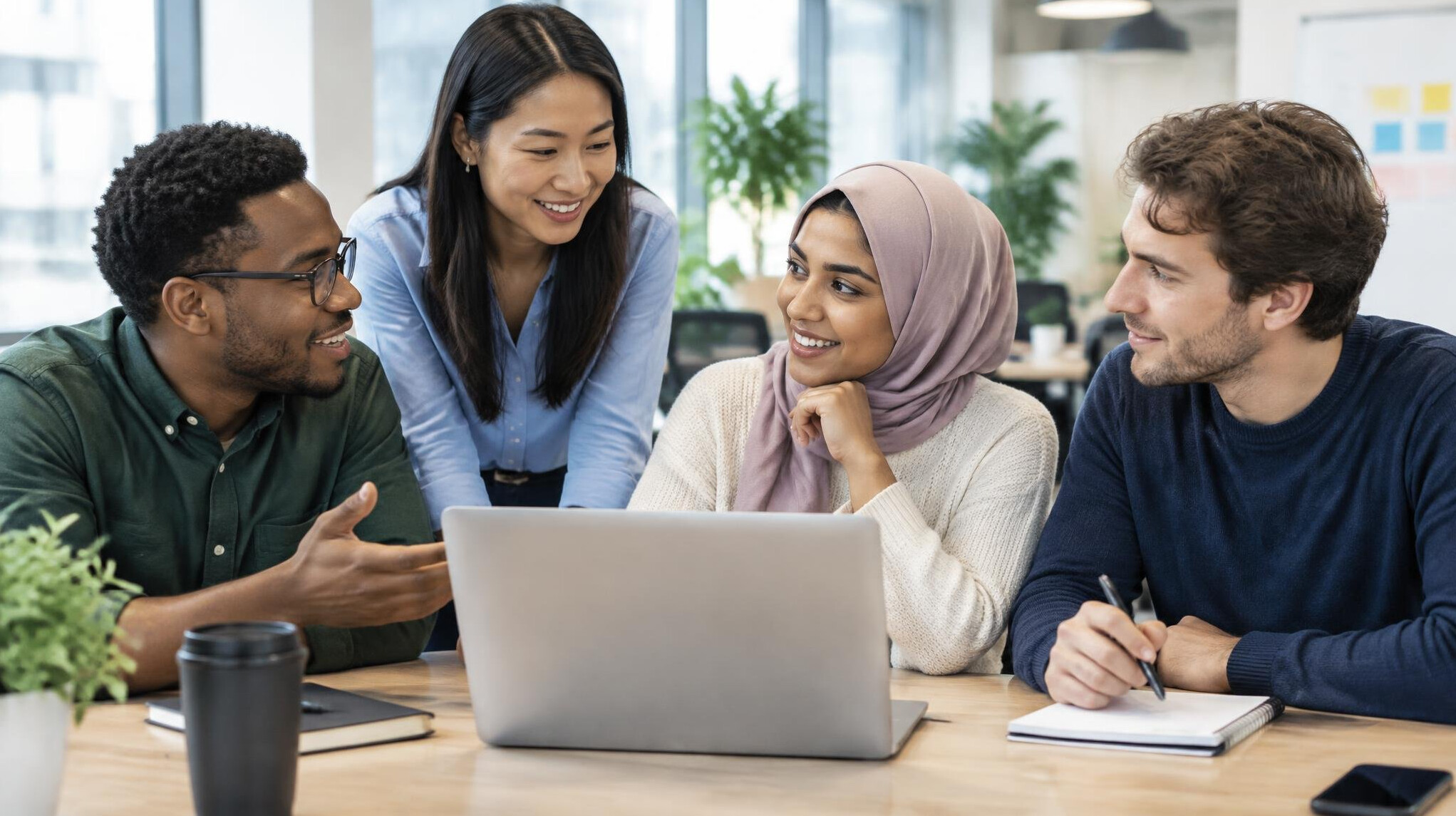 Colleagues collaborating around a laptop